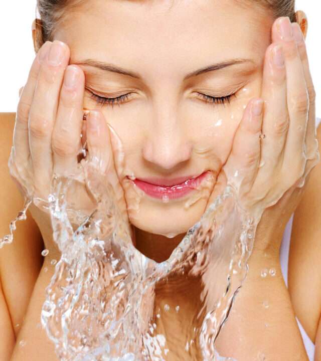 Cute woman wash her face with water