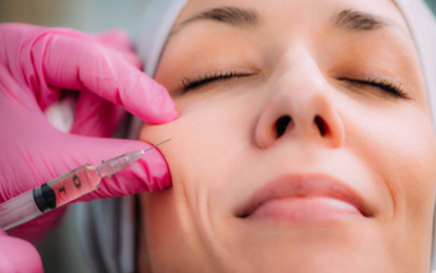 Close-up of a clinician injecting dermal filler into a woman's cheek while she smiles with eyes closed.