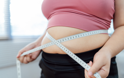 Person in a pink top measures their waist with a tape measure, showing a midsection-focused fitness scene.
