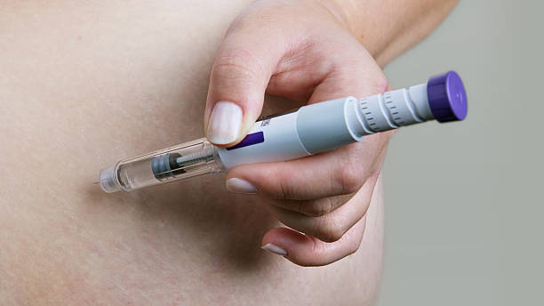 Close-up of a hand injecting insulin into the abdomen with an insulin pen for diabetes care.