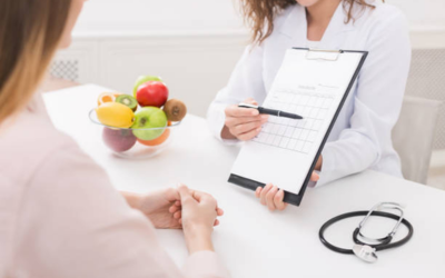 â___Supportive nutrient boosters Healthcare professional reviews a chart with a patient during a nutrition/medical appointment; fruit bowl and stethoscope on the desk.