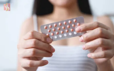 Close-up of a person’s hands holding a blister pack of pink and white pills.