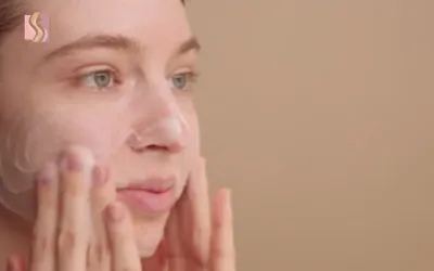 Close-up of a woman massaging facial cream into her cheeks during a skincare routine.